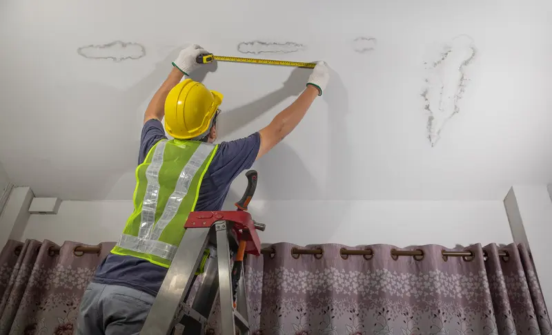 Worker fixes leaking pipe in ceiling, close-up of a stain on the ceiling