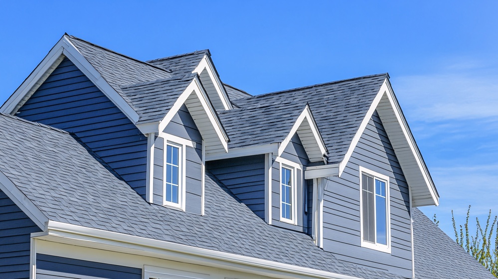 Dormer windows on the sloped shingle roof of a newly built house in Brighton, Massachusetts, USA