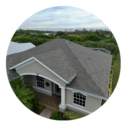 A house featuring a sloped roof and a paved driveway leading up to the entrance.